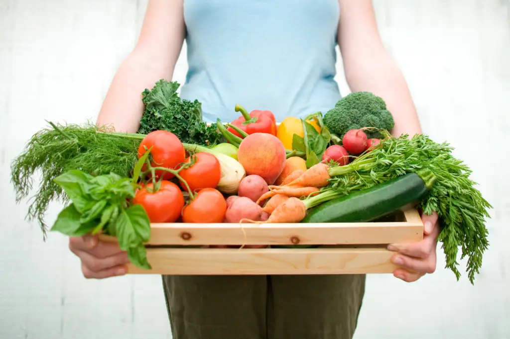 woman holding box of healthy vegetables